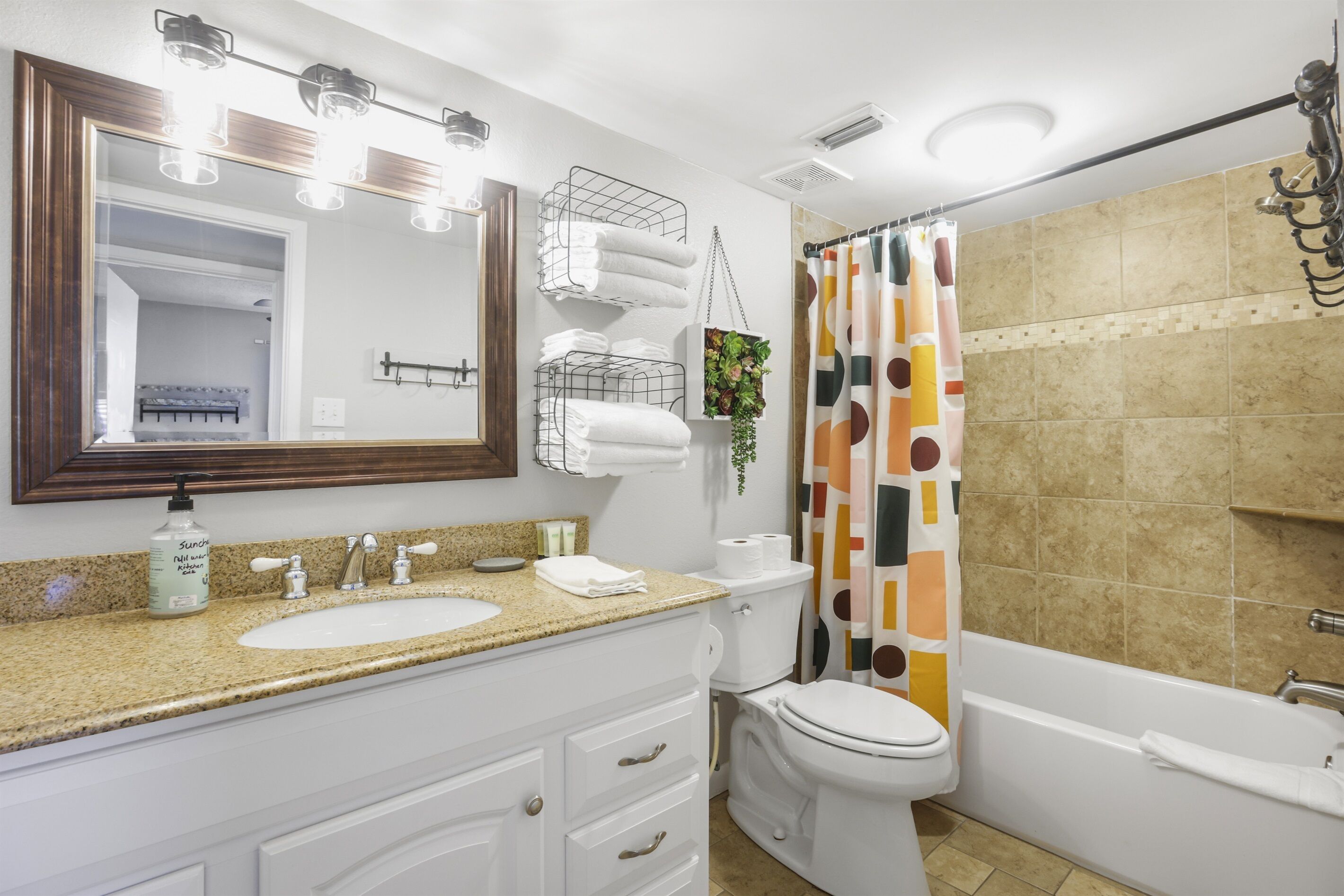 Une salle de bain équipée d’un lavabo, d’un miroir, d’un porte-serviettes, de toilettes et d’une baignoire.