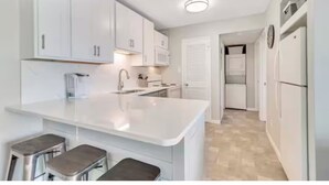 A modern kitchen with white cabinetry, a central island with stools, and a built-in oven.