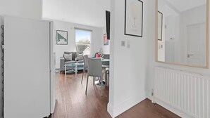 Een moderne keuken met een inbouwkoelkast, een eethoek met tafel en stoelen, en een groot raam dat voor natuurlijk licht zorgt.