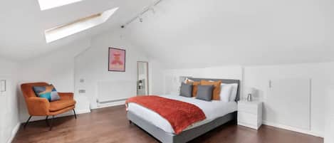 Un dormitorio con tragaluz, una cama, una mesita de noche, una silla y un radiador.