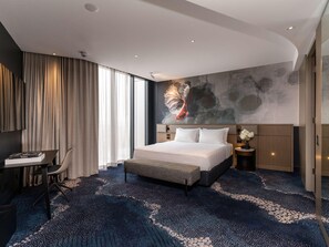Una habitación de hotel moderna con una cama grande, un escritorio y vistas a la ciudad.