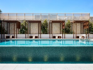 A swimming pool with a stone wall, wooden pergolas, and seating areas. - Novotel Sydney Cabramatta (Sydney)