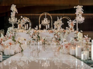 A luxurious setting with a reflective floor, elegant floral arrangements, and chandeliers.