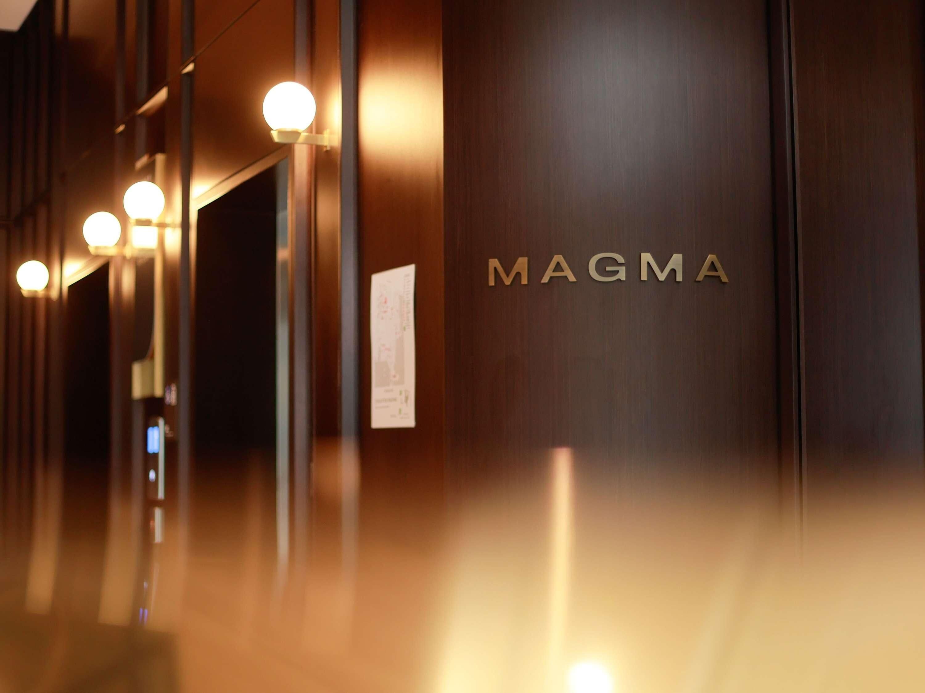 A hallway with a sign reading 'MAGMA' and a wall-mounted light fixture.