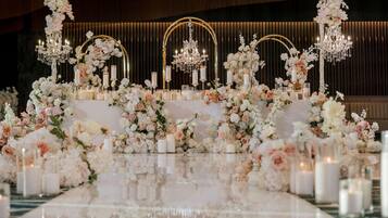 Un ambiente lujoso con suelo reflectante, arreglos florales elegantes y candelabros.