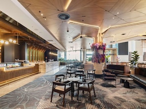 A modern hotel lobby with a central seating area, a reception desk, and a large decorative vase.