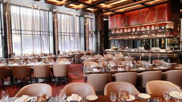 Un restaurant doté de nombreuses tables, d’un bar et de grandes fenêtres.