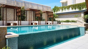 A swimming pool with a tiled edge, stone walls, and a pergola structure. - Novotel Sydney Cabramatta (Sydney)