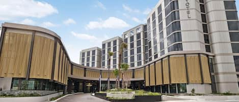 Een modern hotel met een gebogen gevel, meerdere verdiepingen en een opvallend 'NOVOTEL'-bord.