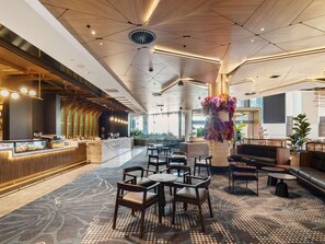 A modern hotel lobby with a central seating area, a reception desk, and a large decorative vase.