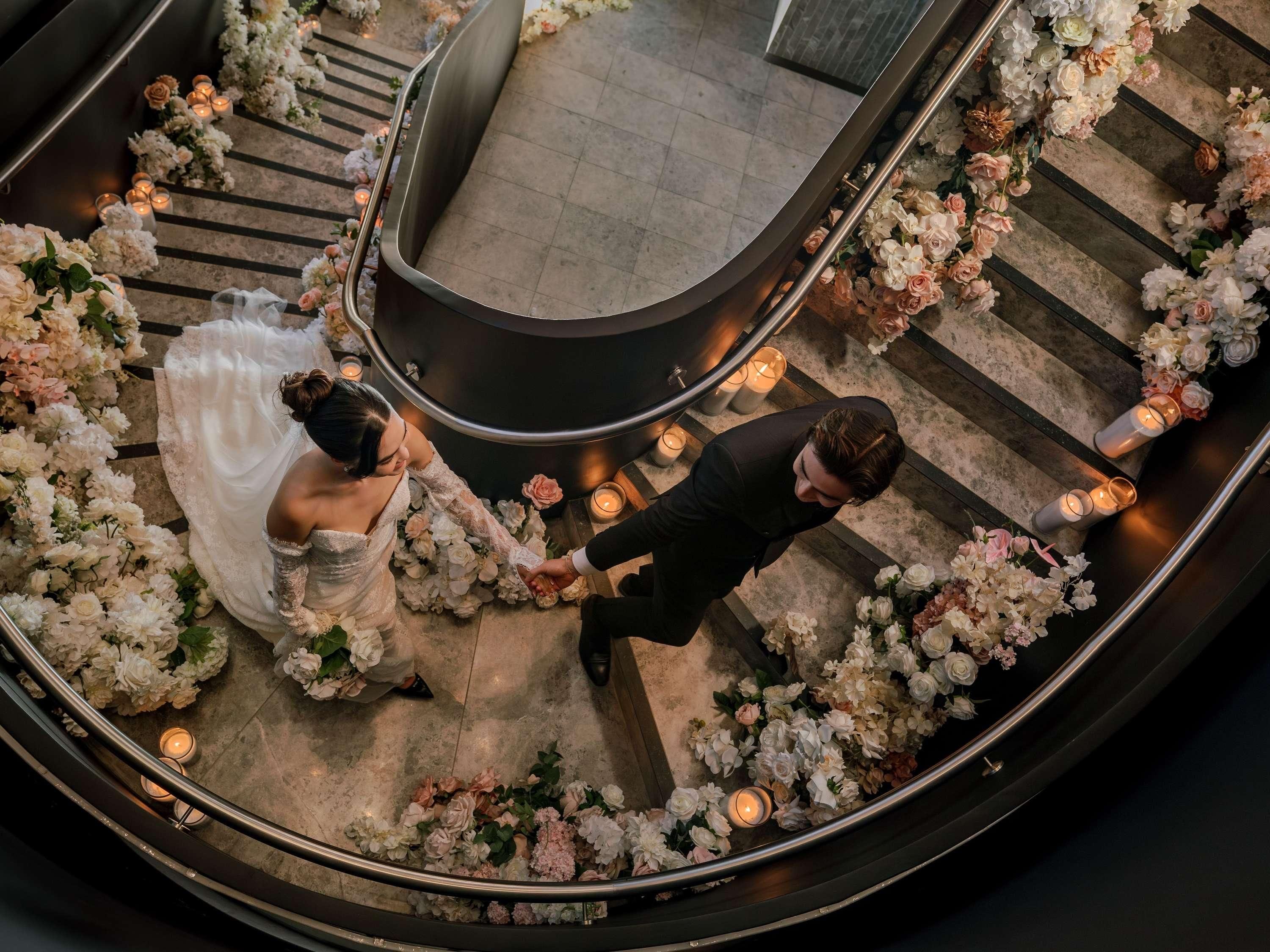 Une cérémonie de mariage se déroulant sur un escalier en courbe, agrémentée de compositions florales et de bougies.