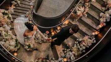 Une cérémonie de mariage se déroulant sur un escalier en courbe, agrémentée de compositions florales et de bougies.