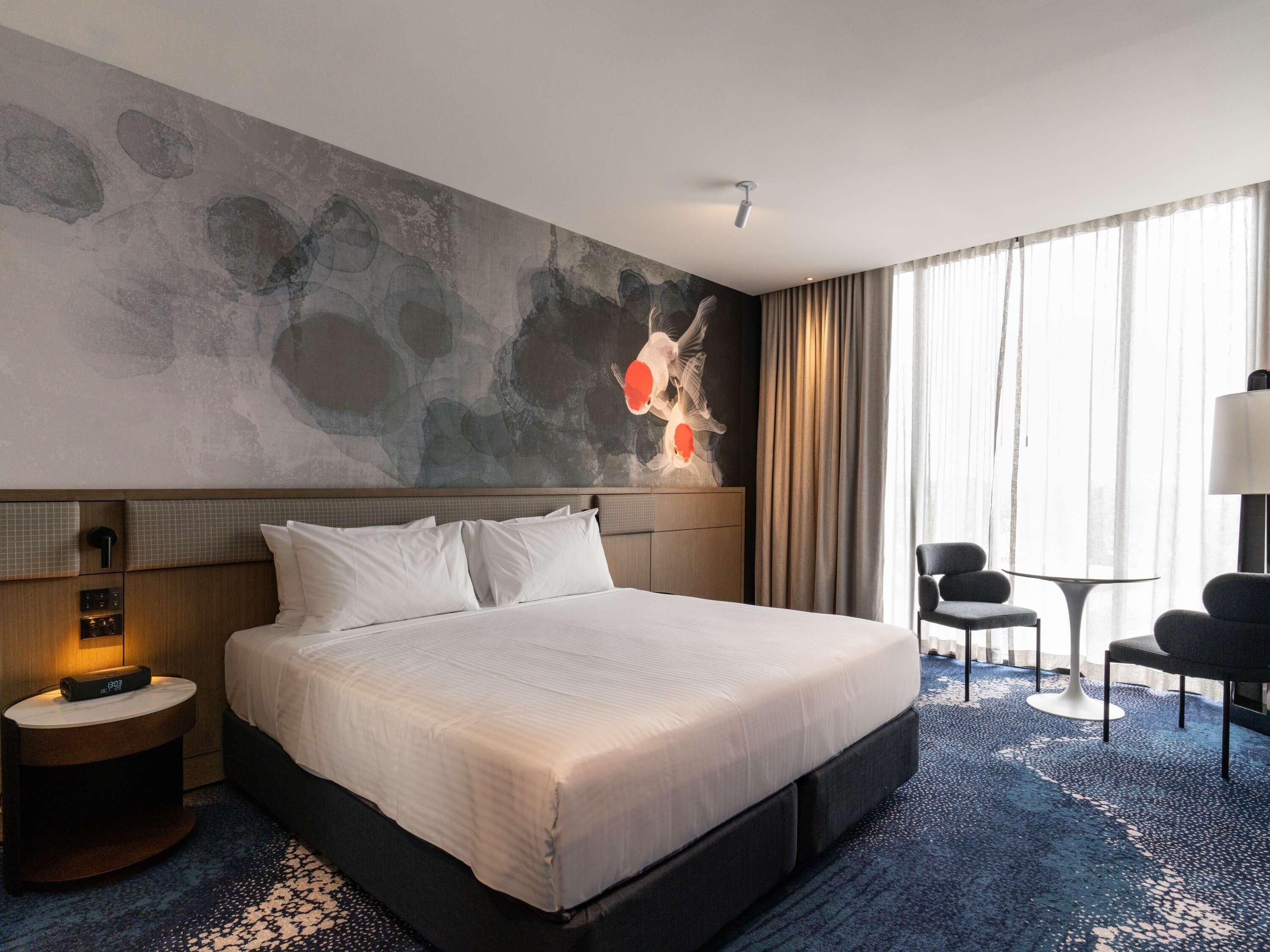 Una habitación de hotel con una cama grande, un escritorio, una silla y un cuadro en la pared.