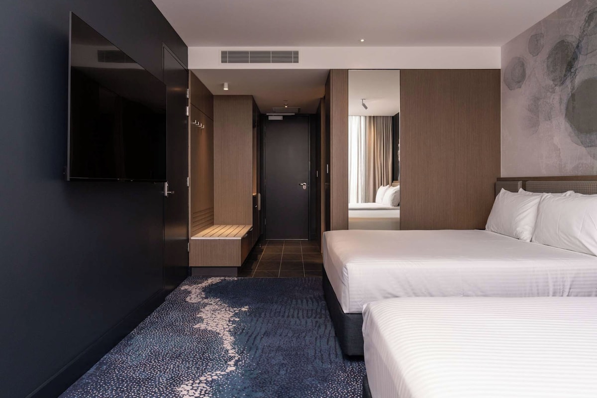 A modern hotel room with a large bed, a TV, and a walk-in closet.