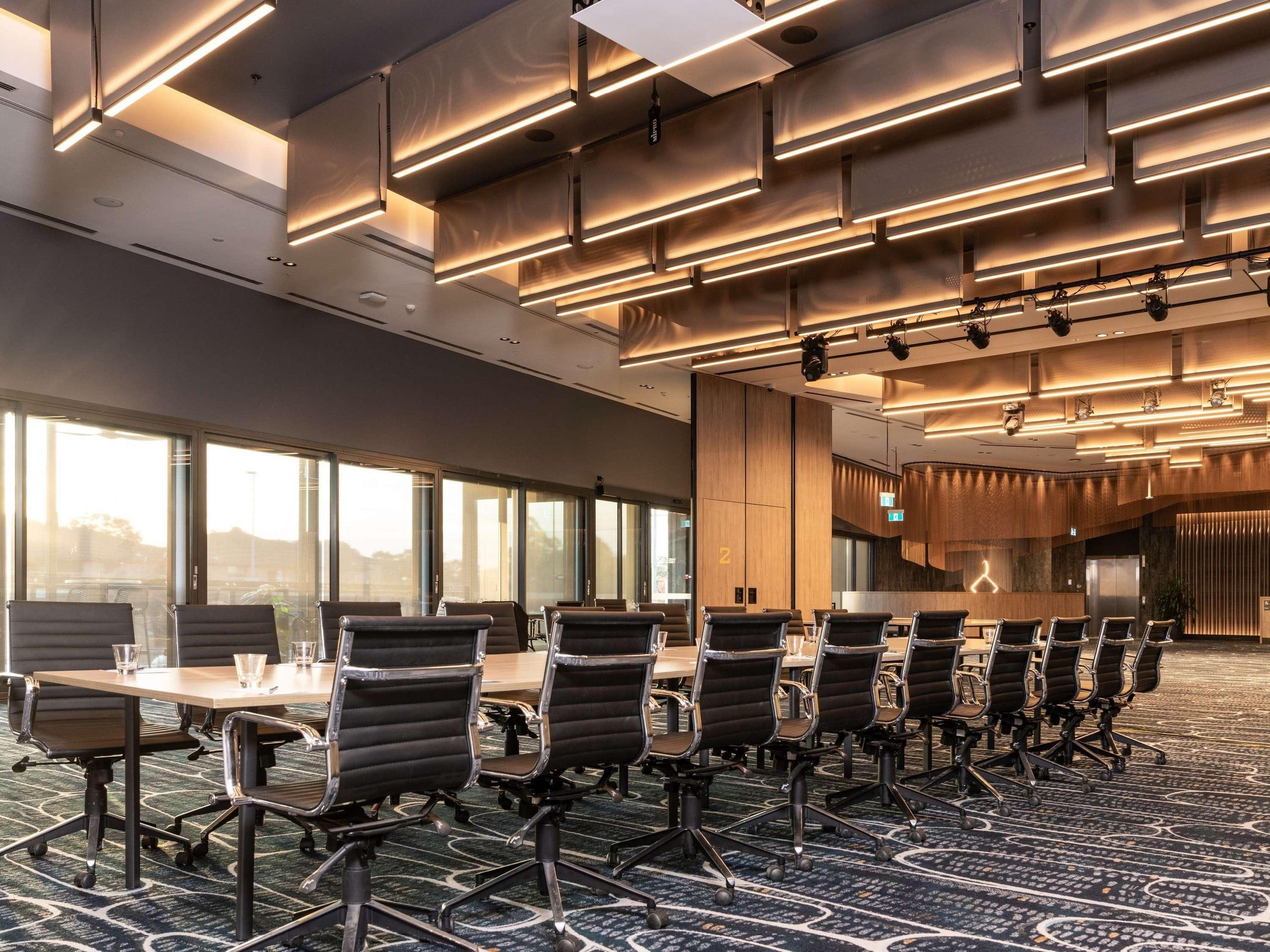 A conference room with a long table and chairs, large windows, and modern lighting.