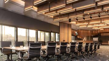 A conference room with a long table and chairs, large windows, and modern lighting.