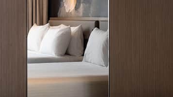 A hotel room with a bed, pillows, a painting on the wall, and wooden paneling.
