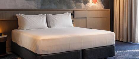 Ein Hotelzimmer mit einem großen Bett, einem Bettkopf mit strukturierter Gestaltung, einer Wandmalerei und einem Fenster mit Vorhängen.