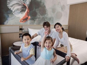 A family in a hotel room with a bed, a round table, and a wall with a fish painting. - Novotel Sydney Cabramatta (Sydney)