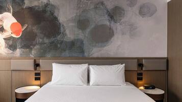 Una habitación de hotel moderna con una cama grande, dos mesitas de noche, una pared con arte abstracto y un cabecero de madera.