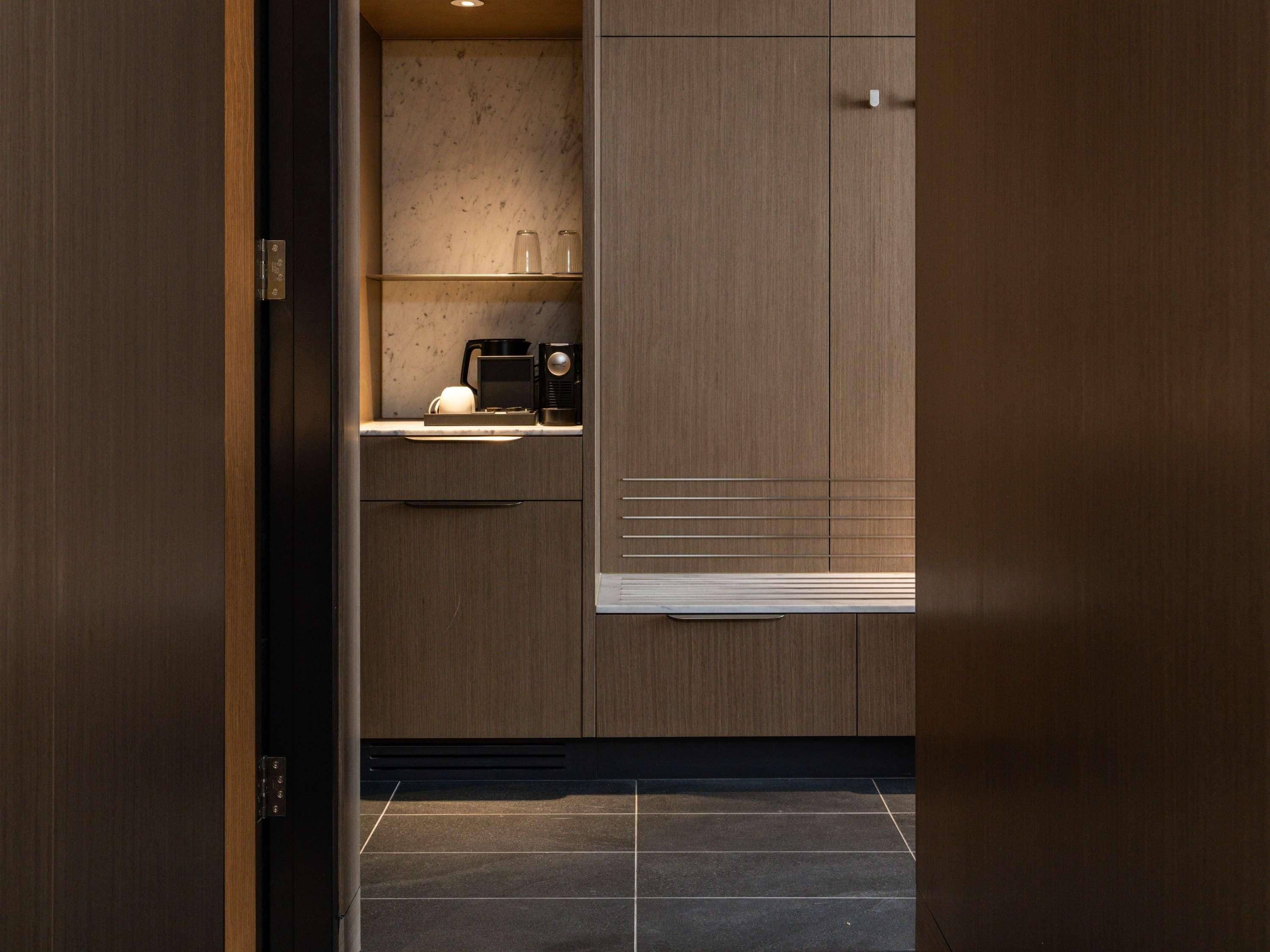 A modern kitchen with a built-in coffee maker, a microwave, and a small window.