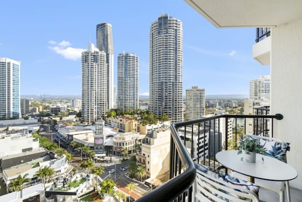 A balcony with a view of a cityscape, including tall buildings and palm trees.