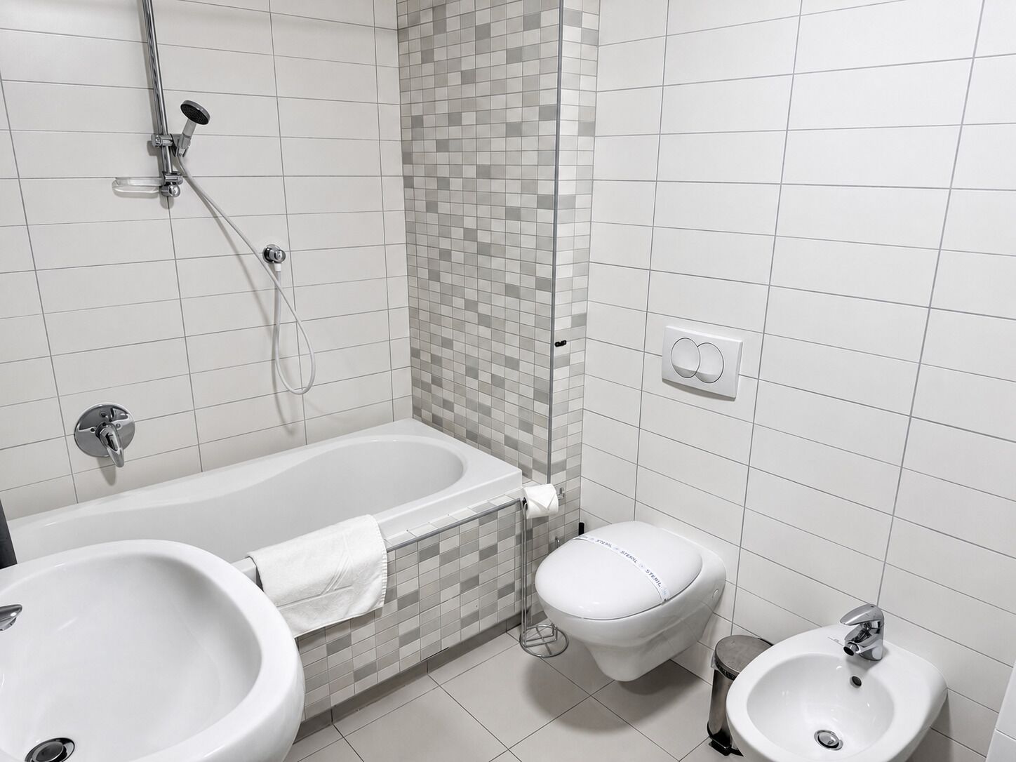 A modern bathroom with a bathtub, two sinks, and a toilet.