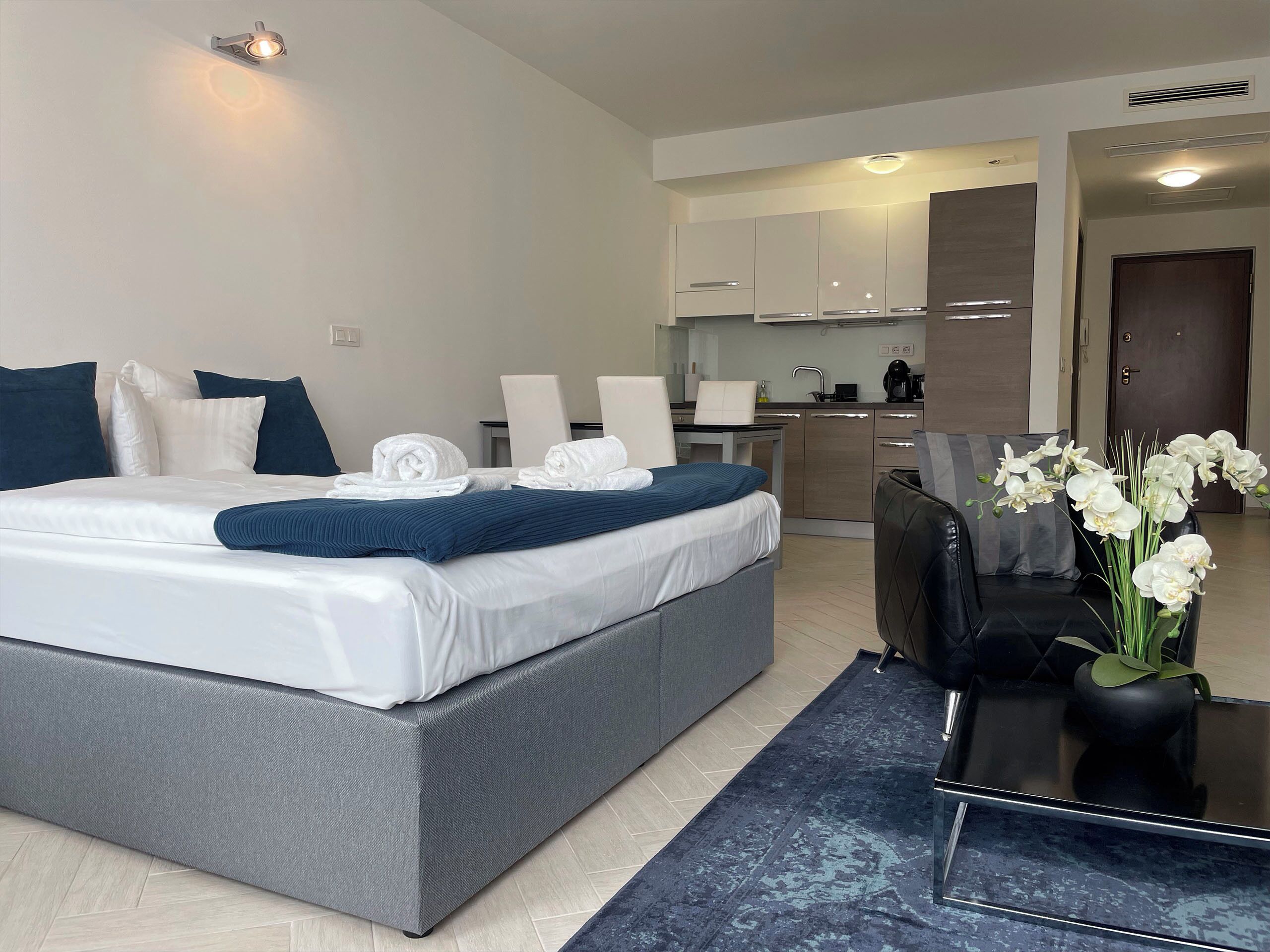 Una habitación de hotel moderna con una cama grande, un área de comedor y una kitchenette.