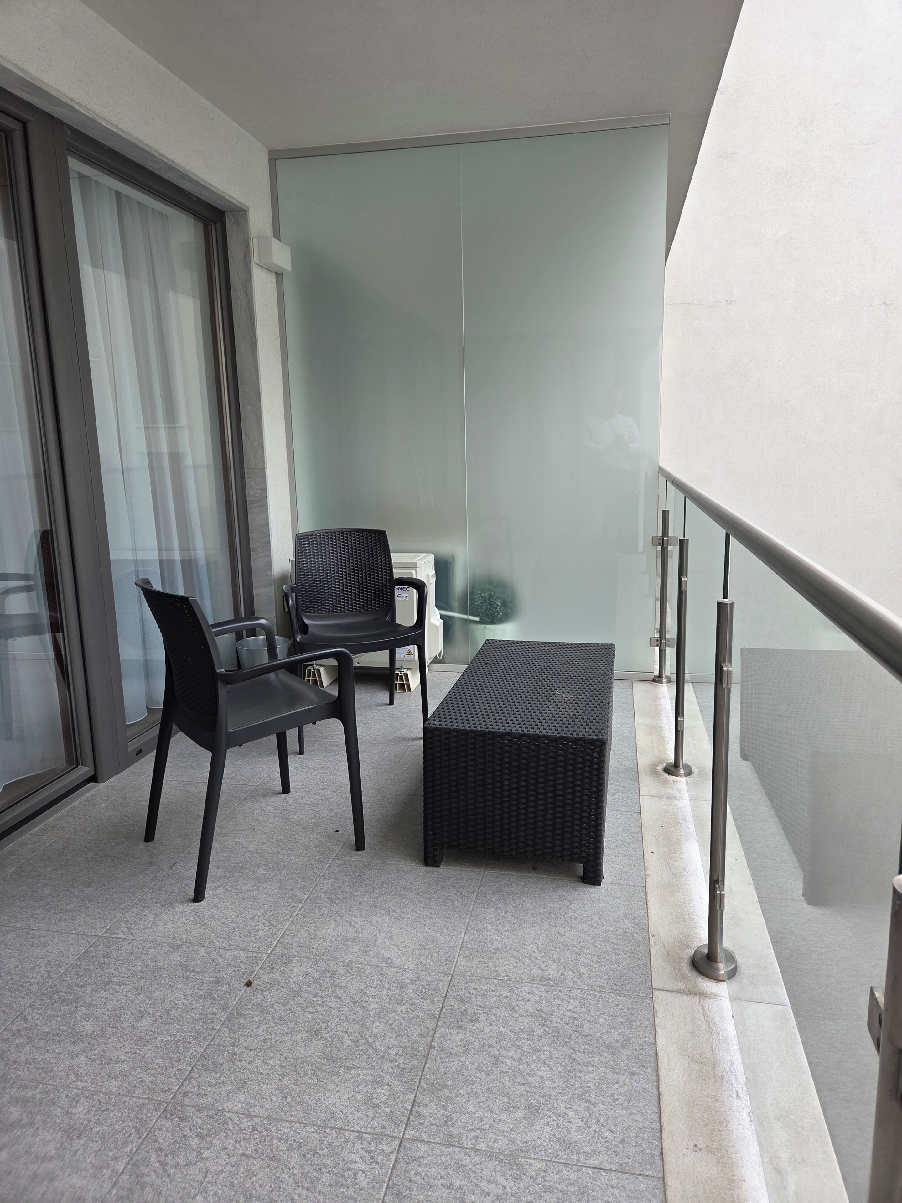 A balcony with a seating area, a table, and a glass partition.