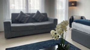 Una sala de estar moderna con un sofá gris, un tapete azul y orquídeas blancas.