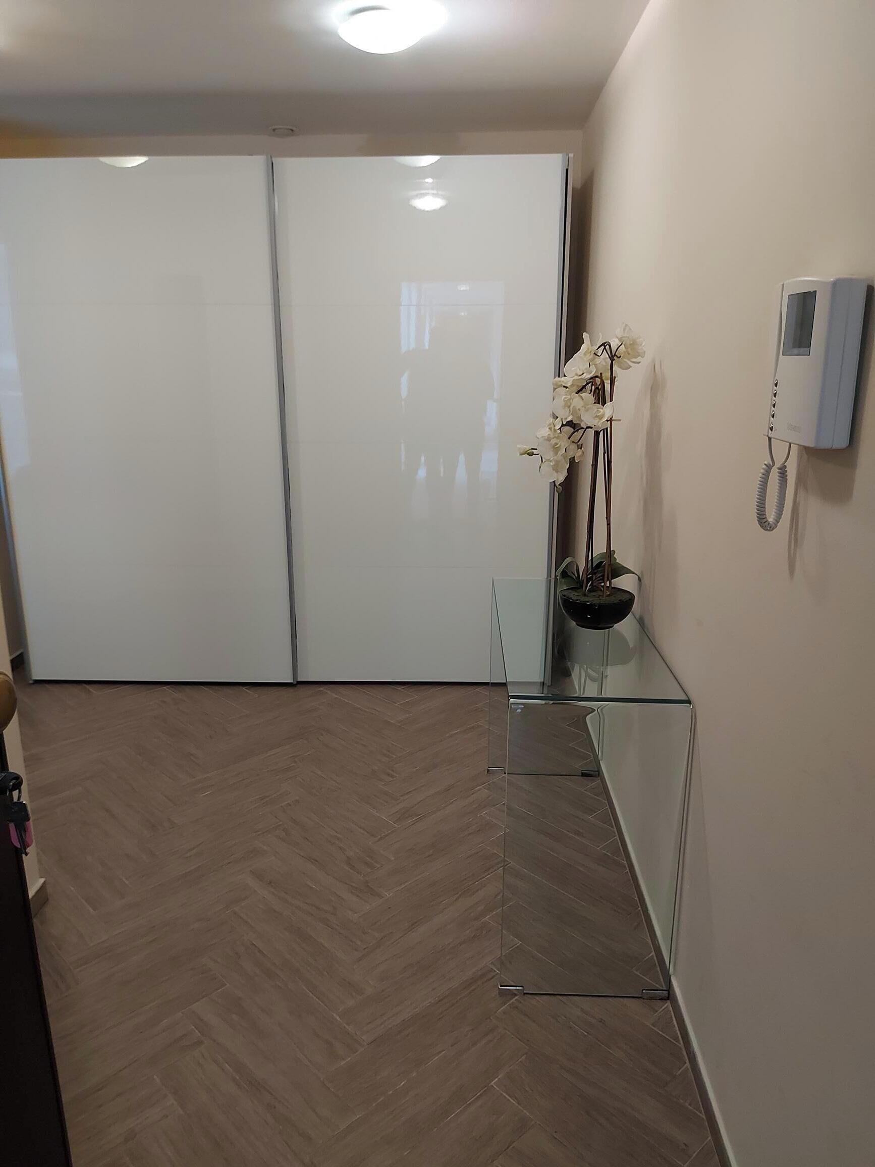 A hallway with a glass partition, a white telephone, and a potted orchid.