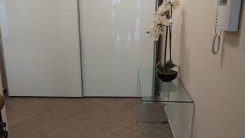 A hallway with a glass partition, a white telephone, and a potted orchid.