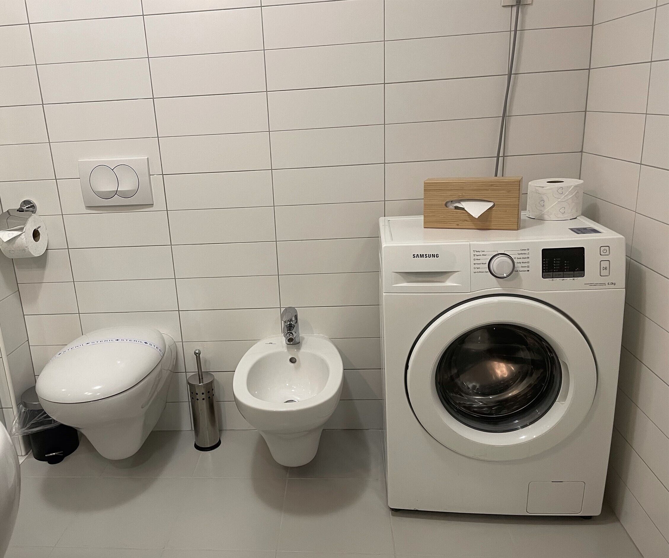 A bathroom with a toilet, bidet, and a washing machine.