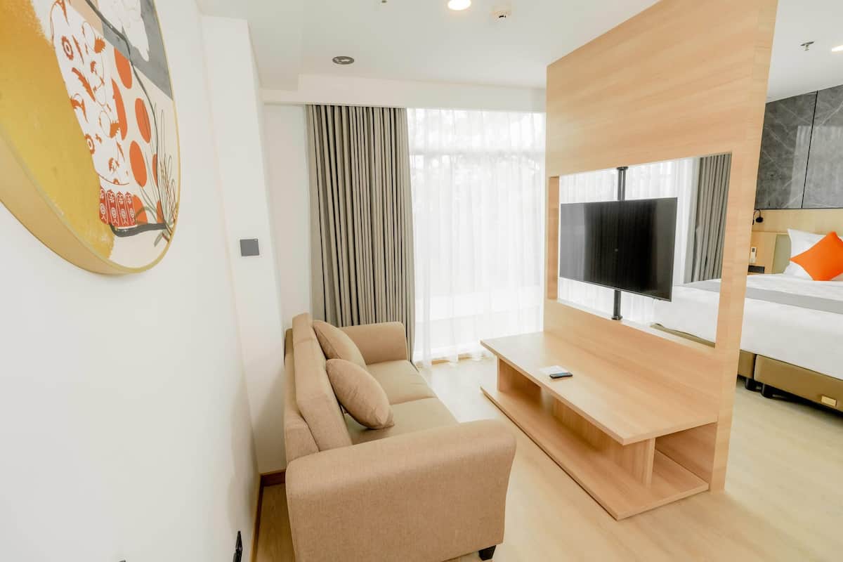 Habitación de hotel moderna con sofá, televisión y cama.