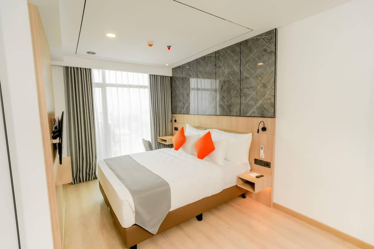 Una habitación de hotel moderna con una cama grande, cabecero de madera y una pared decorativa de mármol.