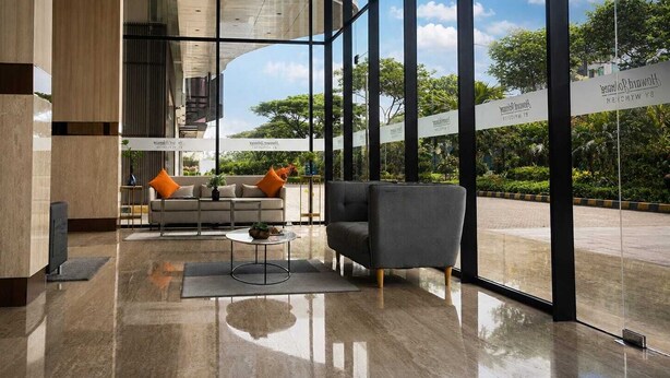 A modern lobby with a sofa, armchair, and coffee table. Large windows offer views of greenery and a building exterior. - Howard Johnson By Wyndham Tangerang (Tangerang)