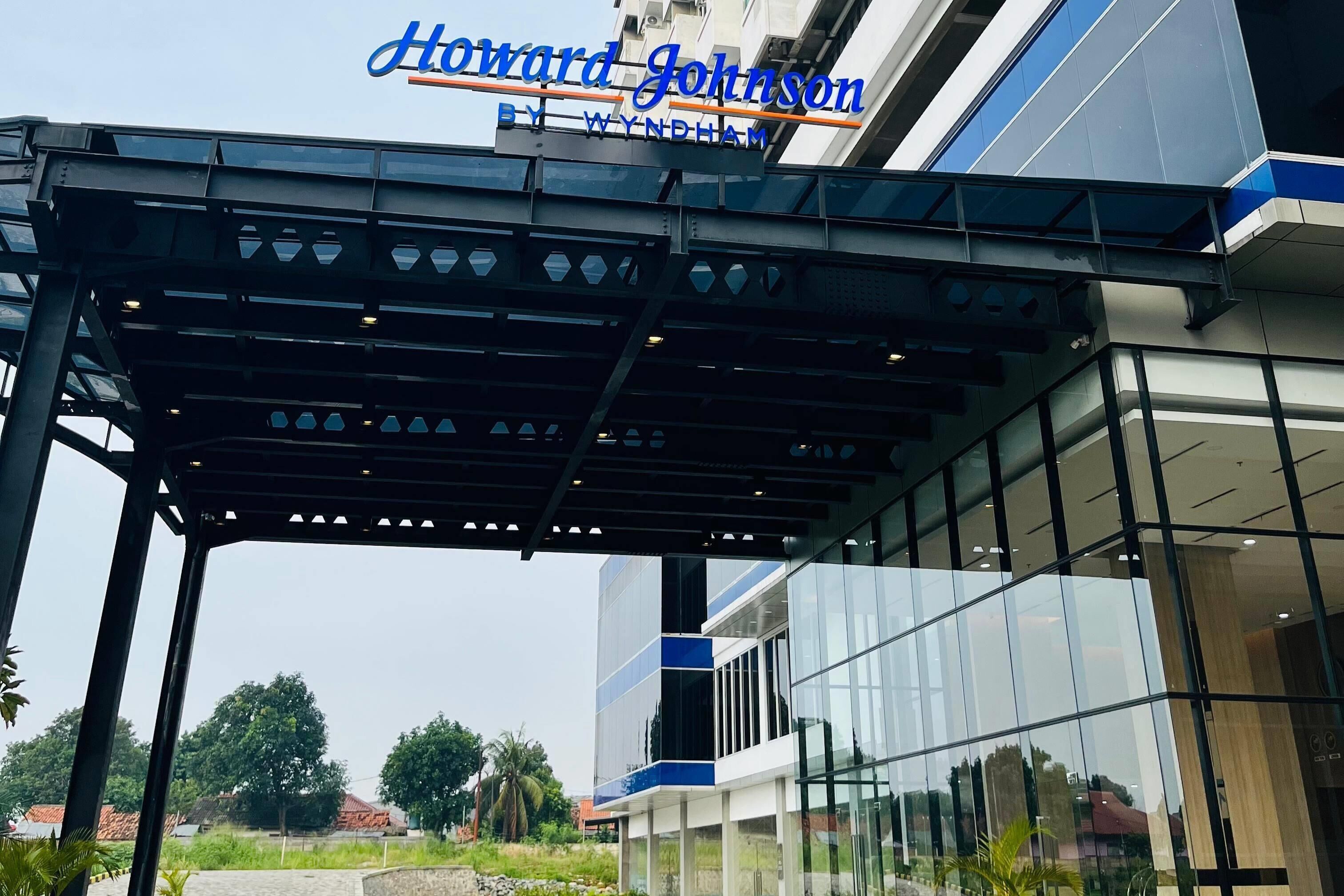 A modern building with a glass facade and a sign reading "Howard Johnson by Wyndham."