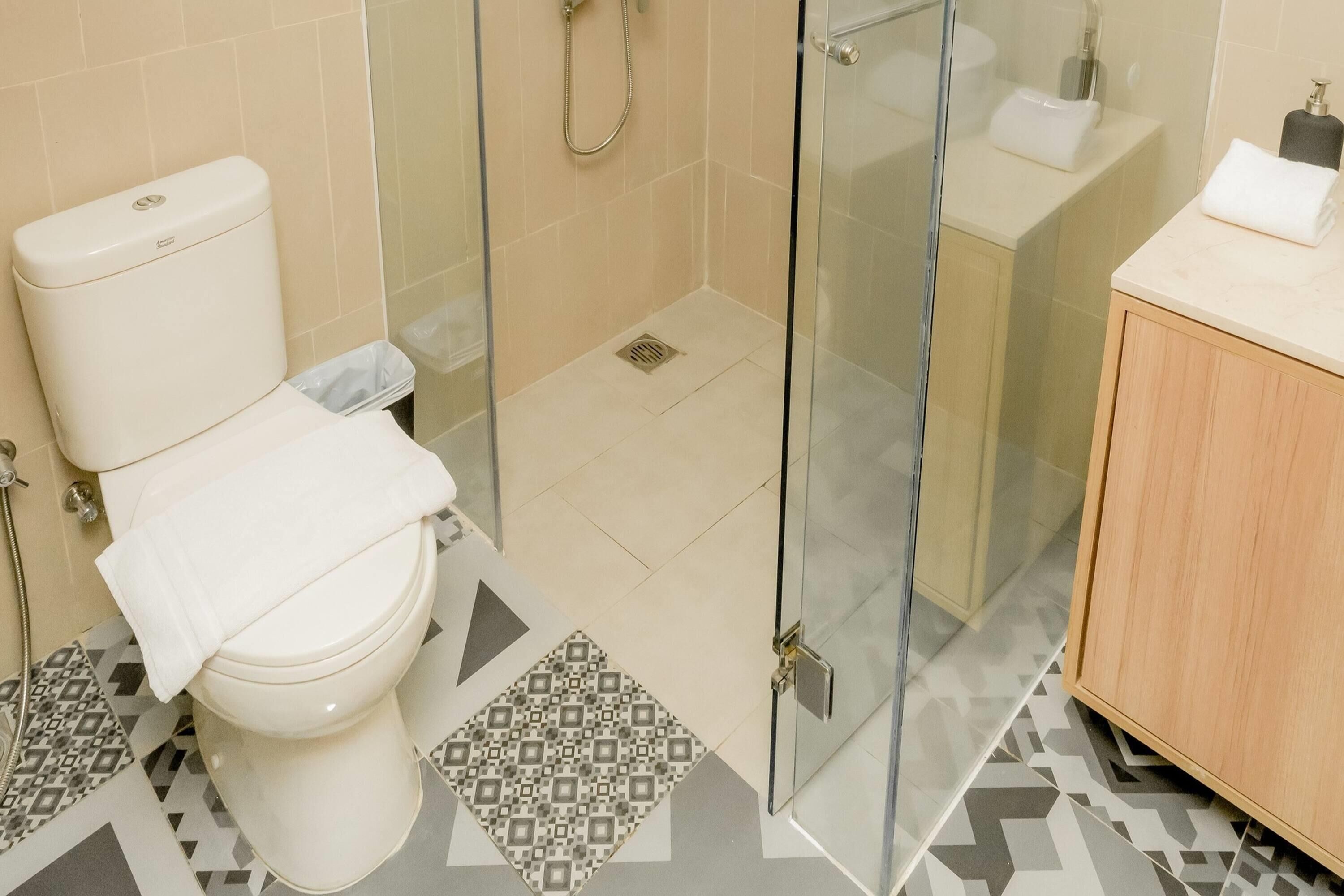 A modern bathroom with a toilet, shower, and glass-enclosed shower area.