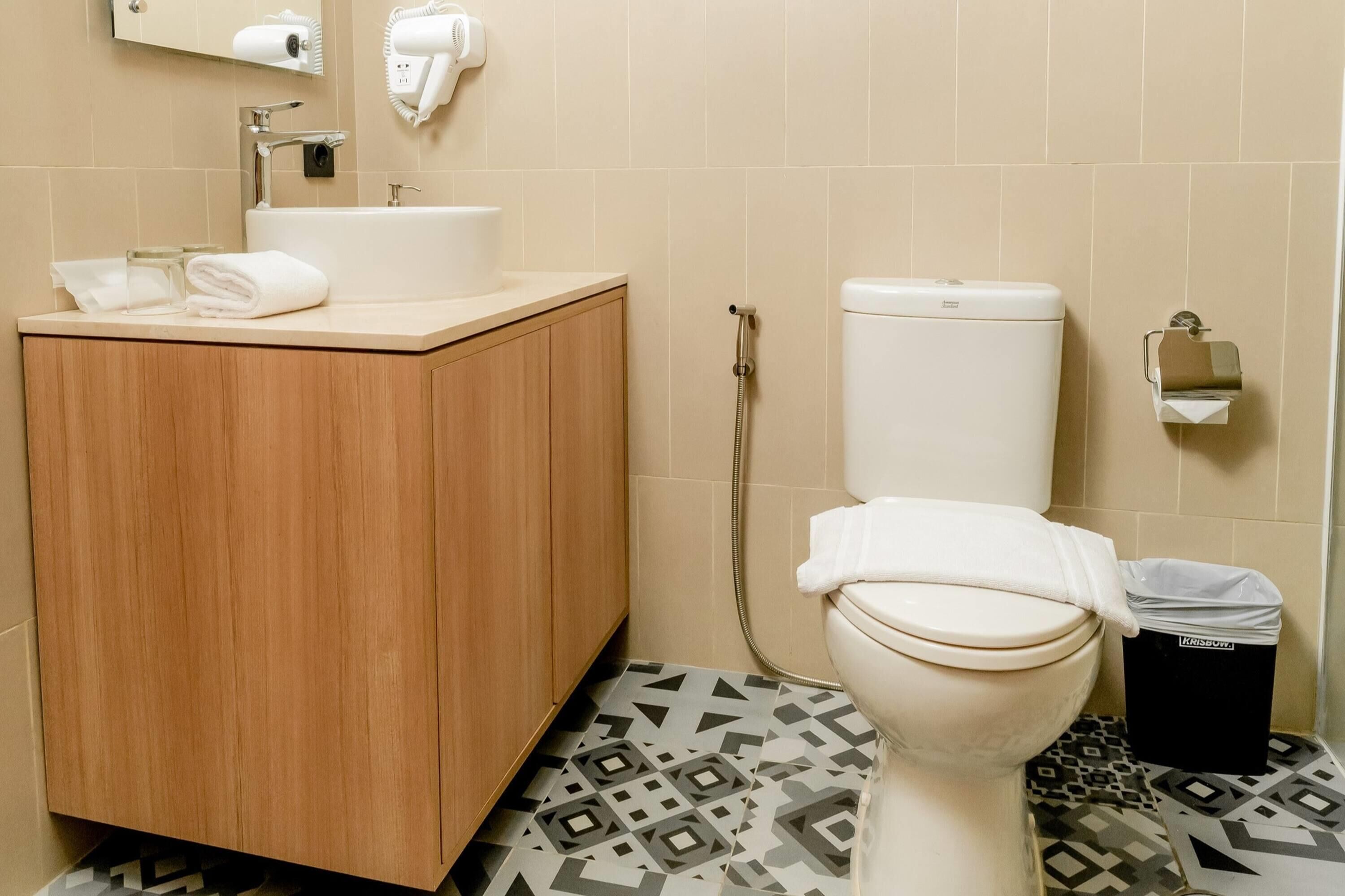A bathroom with a wooden cabinet, a sink, a toilet, and a shower.