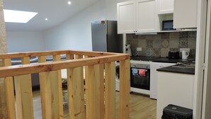 A modern kitchen with white cabinets, a stainless steel refrigerator, and a microwave. - townhouse (saujon)