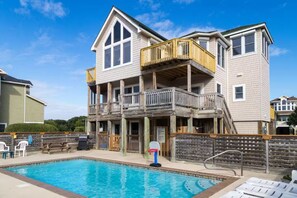 A two-story building with a pool, outdoor seating, and a basketball hoop. - Sandy Pants-Walk to Beach! (Duck)