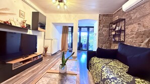 A living room with a flat-screen TV, a sofa, a coffee table, and a potted plant. - Apartment Niko Private Garden Wifi  (Opatija)