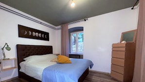 A bedroom with a bed, a nightstand, a dresser, a window with a view of trees, and a wall-mounted picture of moon phases. - Apartment Niko Private Garden Wifi  (Opatija)