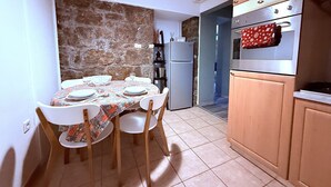 A small kitchen with a dining table set for four, a refrigerator, and a stove. - Apartment Niko Private Garden Wifi  (Opatija)