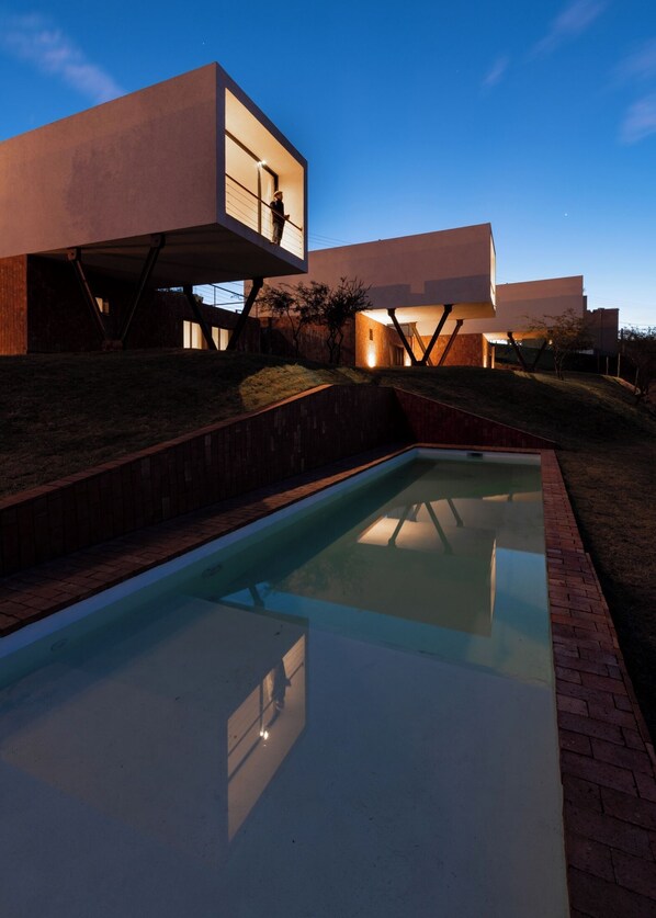 A modern building with a glass pool and a brick pathway.