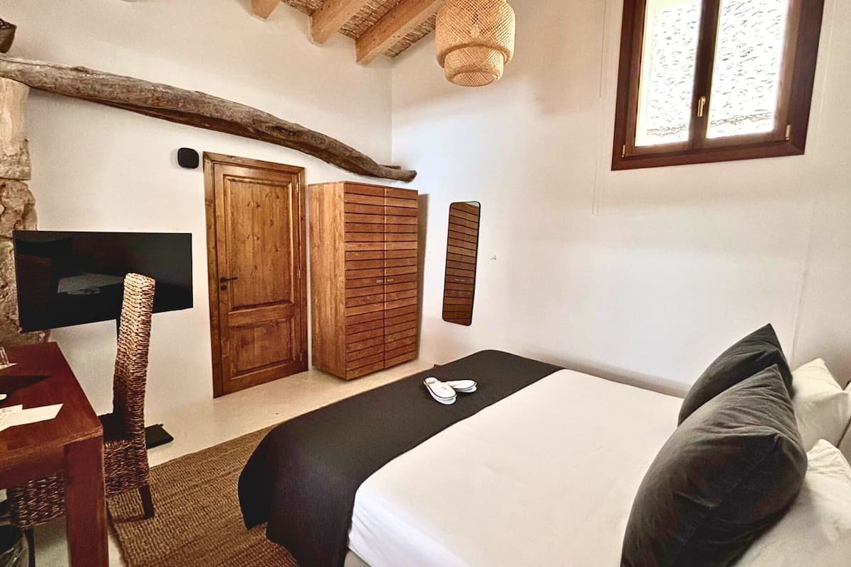 A bedroom with a bed, a desk, a television, and a wardrobe.