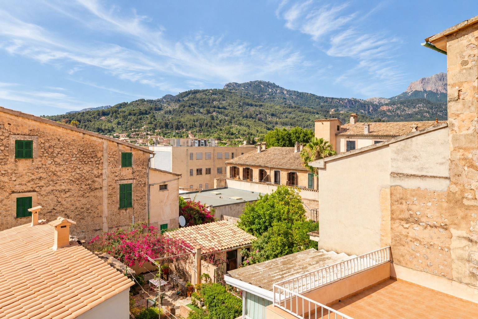 A courtyard with stone buildings, a view of a mountain, and a clear sky.