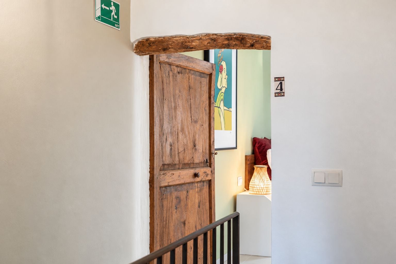 Une porte en bois à l’aspect rustique, un panneau vert indiquant la sortie de secours et un panneau mural portant le chiffre « 4 ».