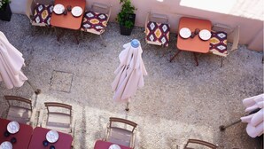 An outdoor seating area with tables and chairs, some with umbrellas, and a potted plant. - Solleric Petit Hotel (Sóller)