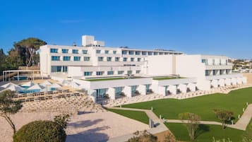 Un hotel moderno con techo plano, varios pisos y una zona de piscina.